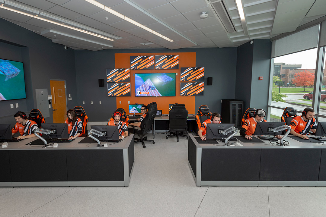 students sitting at three rows of tables competing in online games.