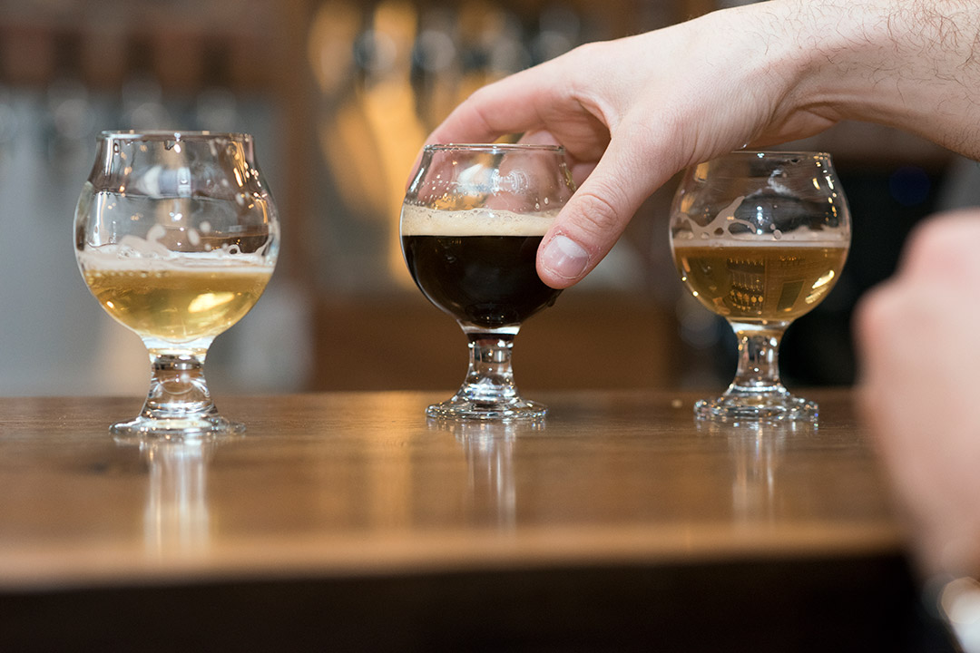 three small glasses of different colored beers.