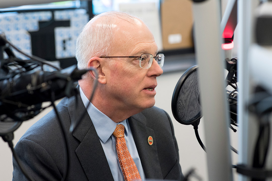 RIT president talking into microphone at radio station.