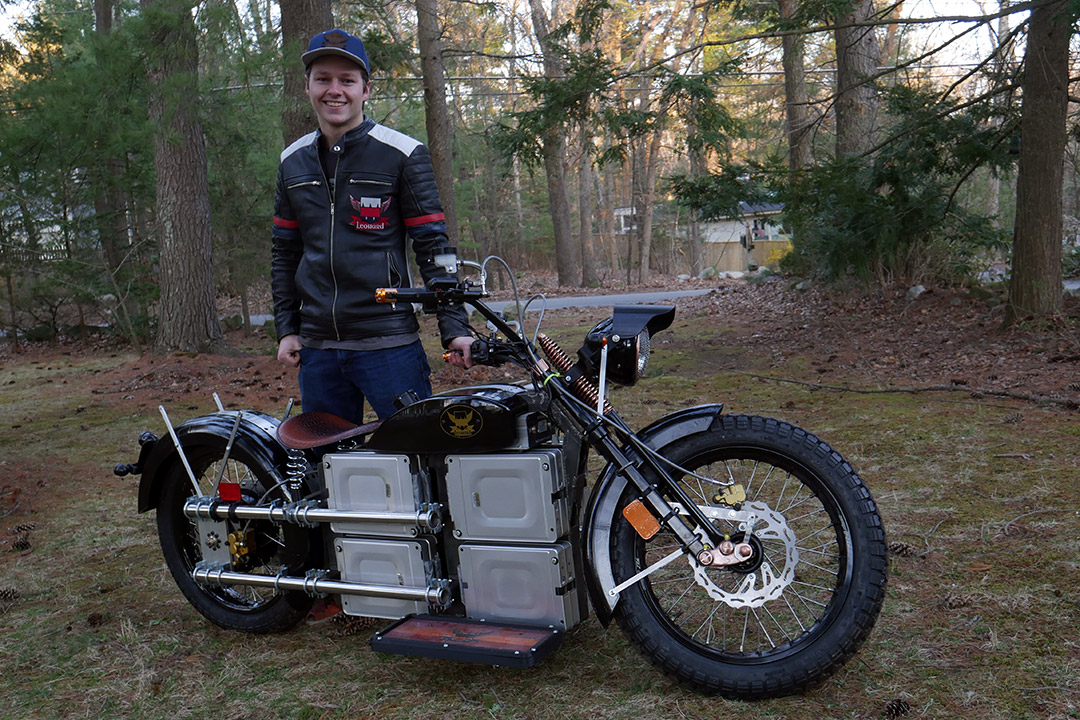 student standing with electric motorcycle.