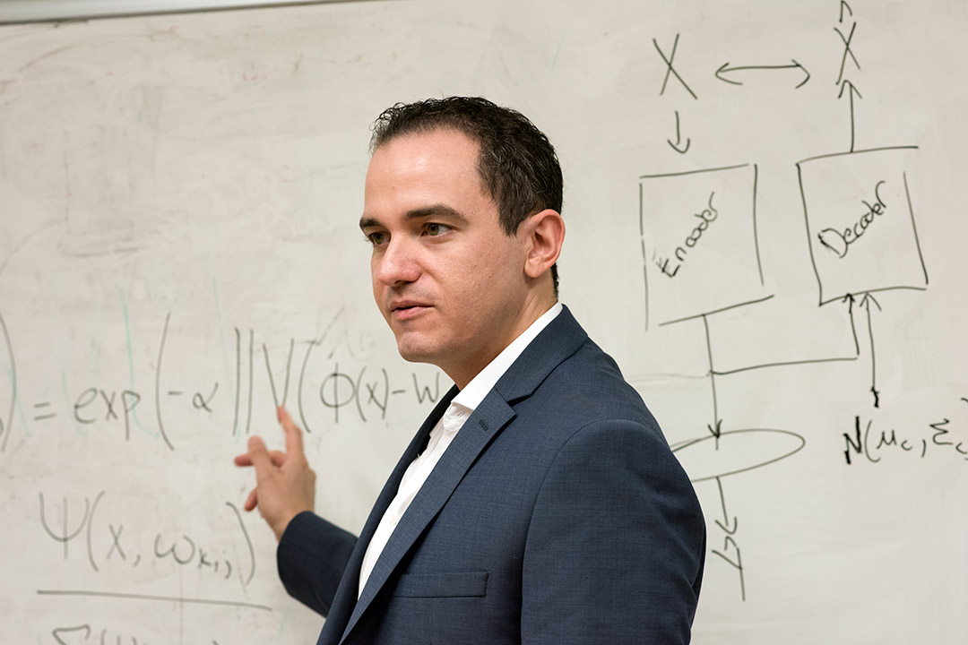 researcher pointing at equations on dry-erase board.