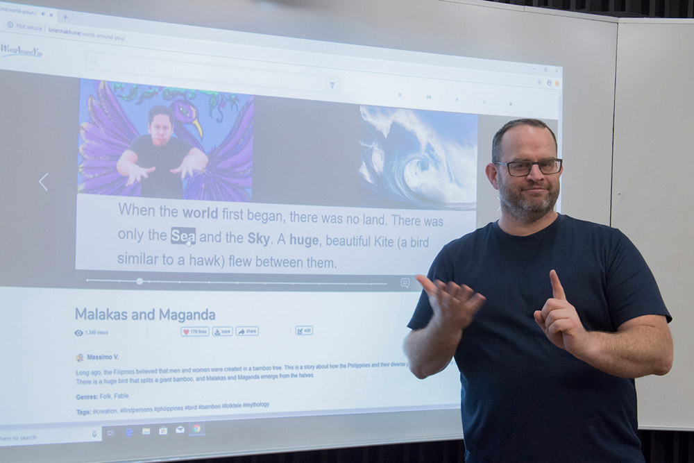 professor using sign language in front of projected presentation.