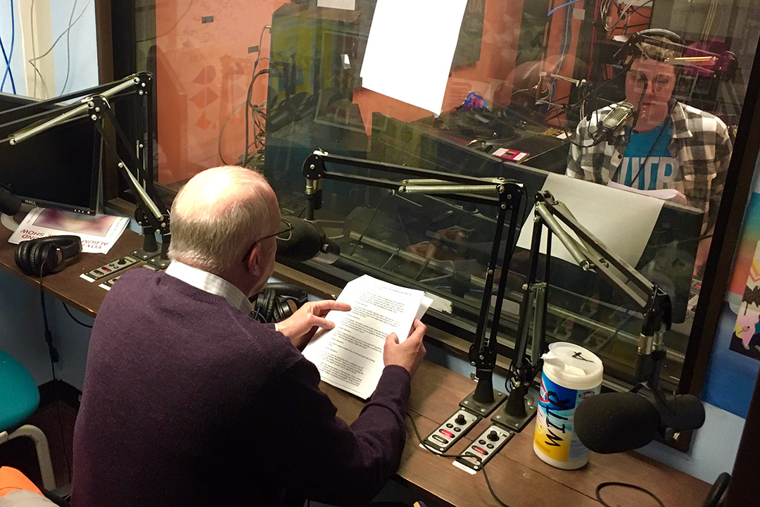 RIT President David Munson speaks into microphone in radio station studio.