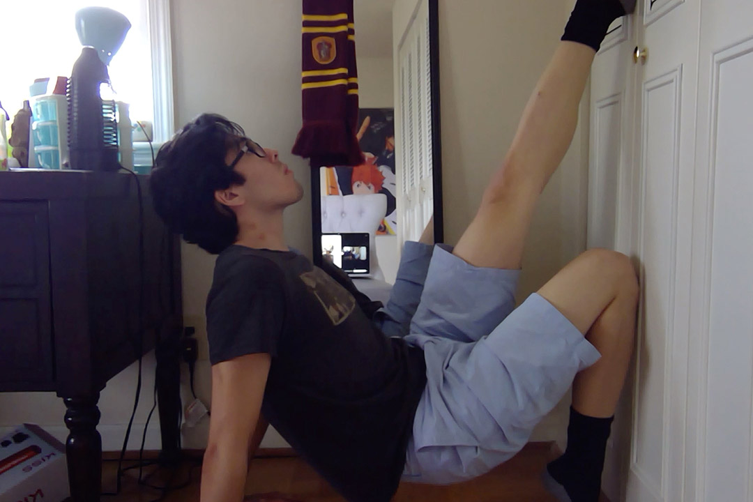 student performing a dance inbetween his closet, desk and wall.