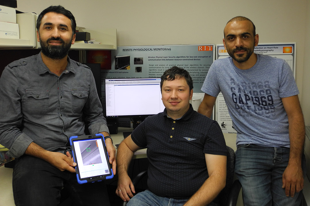 three researchers with one holding a tablet.