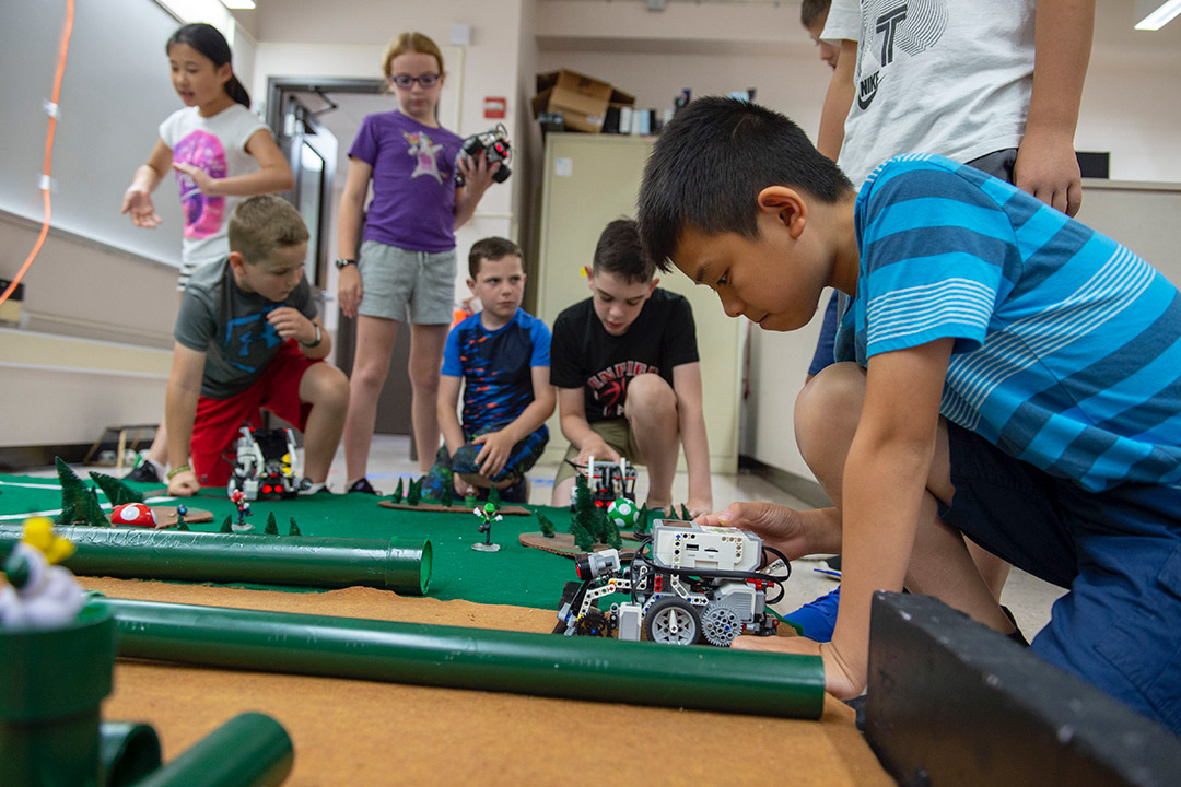 Elementary school children play with small robots they created.