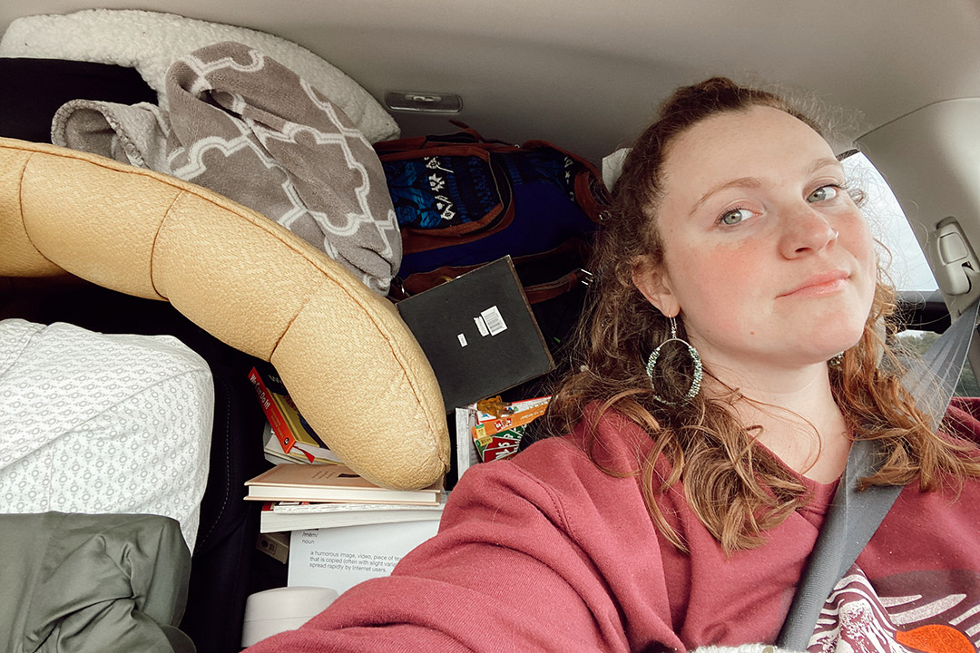 student in driver's seat of car packed with belongings.