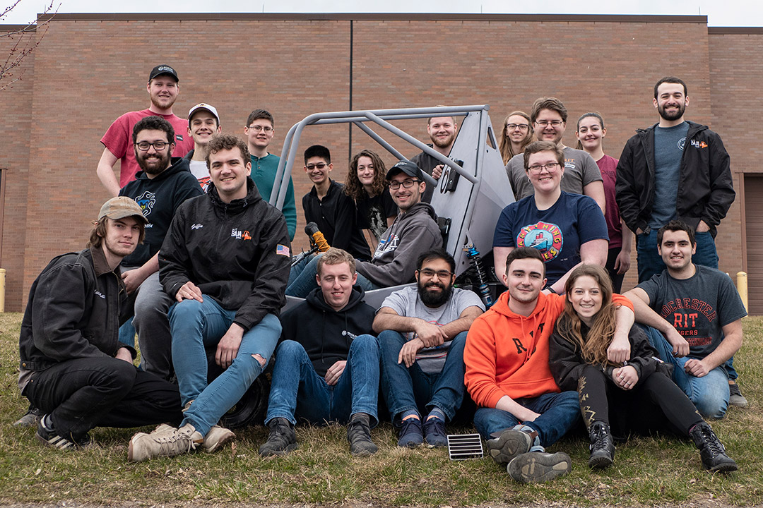 group of students surrounding baja car.