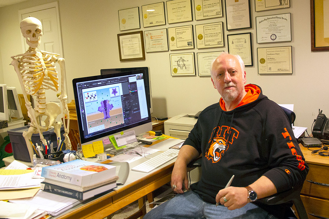 professor posing at desk with certifications and degrees in the background and a human skeleton.