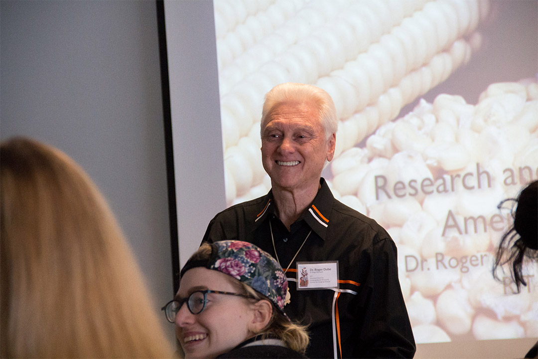 Roger Dube standing in front of a presentation projected onto a screen.