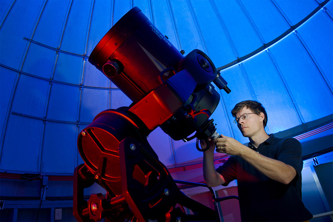 man looking at giant telescope in an observatory.