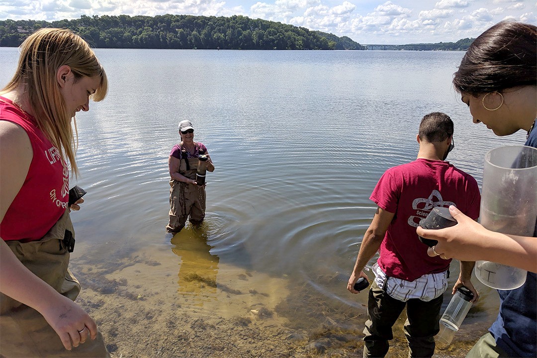 four researchers collecting sediment samples from a lake.