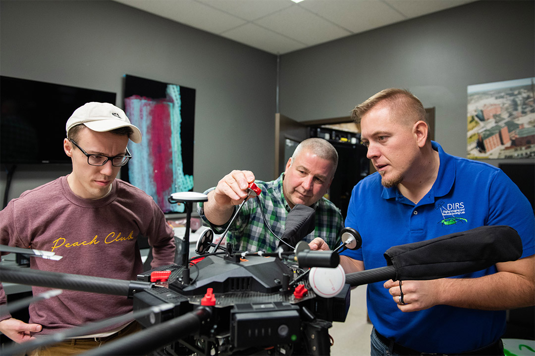 three researchers working on a drone.