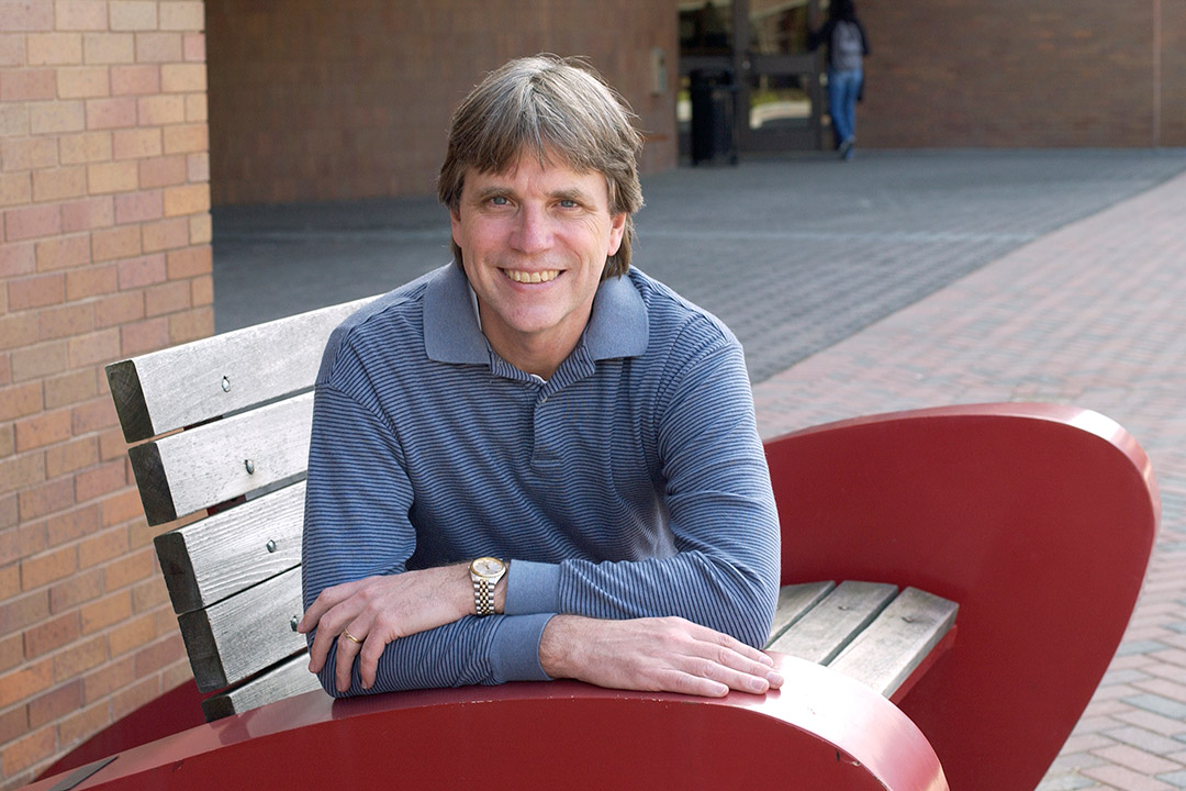 Professor sitting on a bench posing for camera