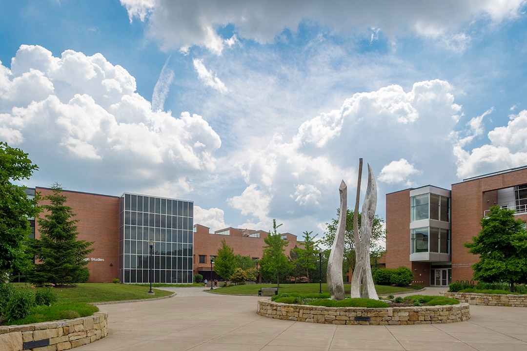 outside of RIT campus, featuring brick and glass buildings and a metal sculpture.