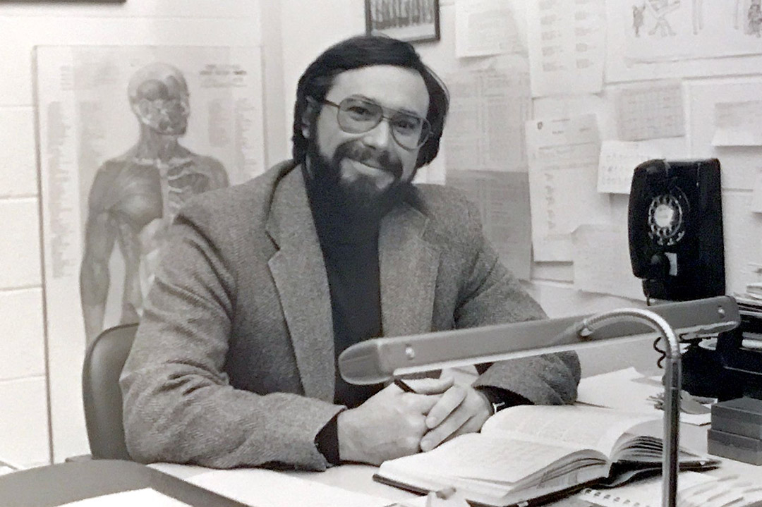 professor sitting at his desk in the 1980s.