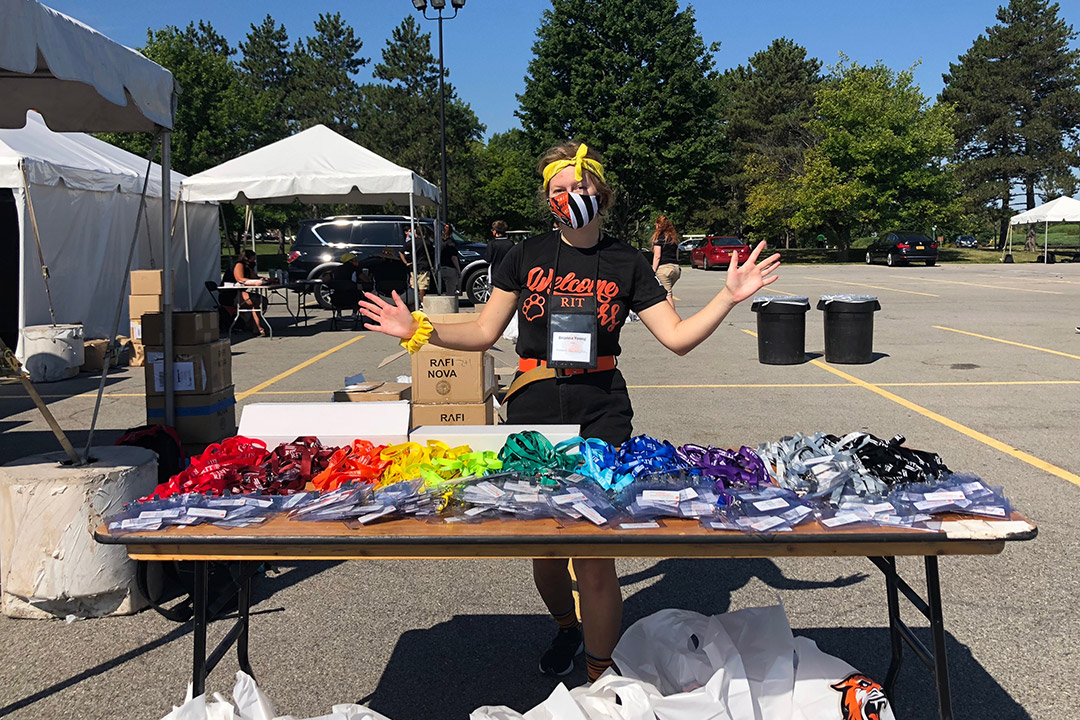 student standing behind table of lanyards and ID badges in a parking lot.