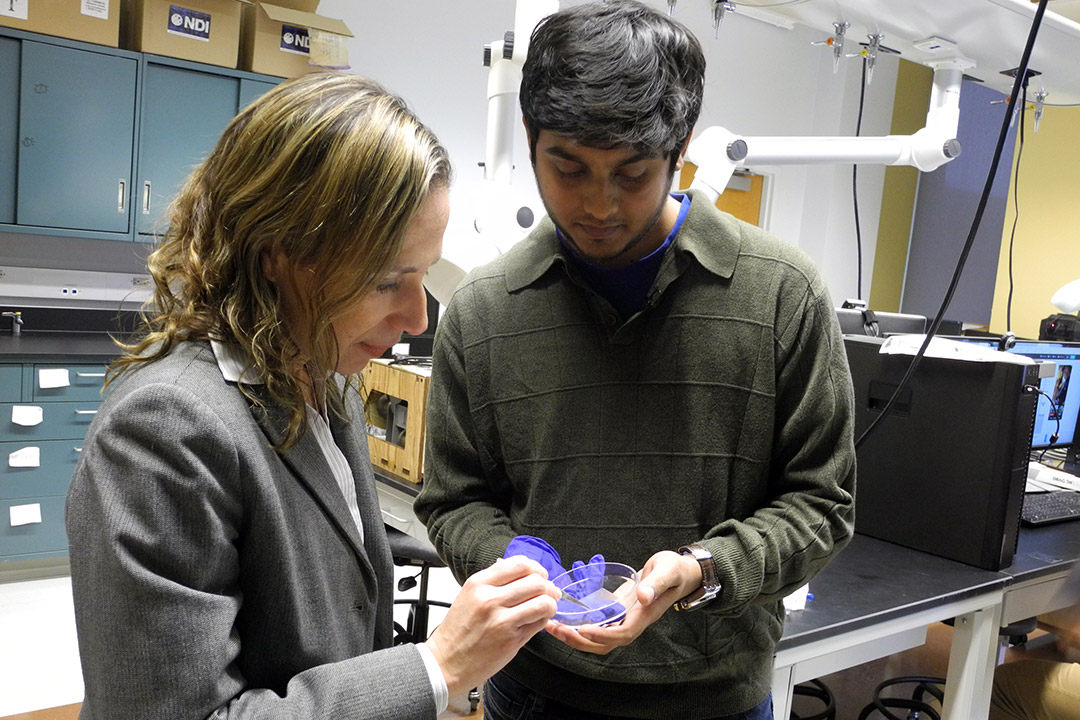 professor and student looking at a petri dish.