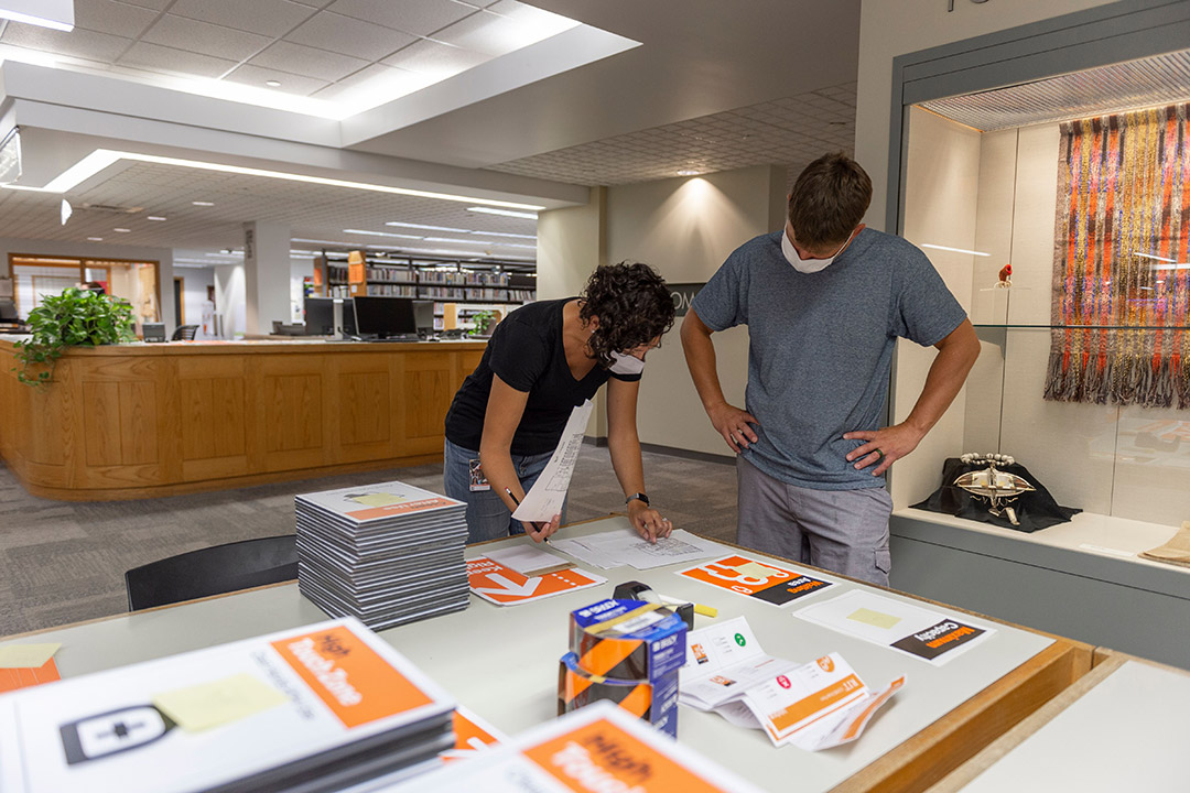 library staff members reviewing new COVID-19 signage.