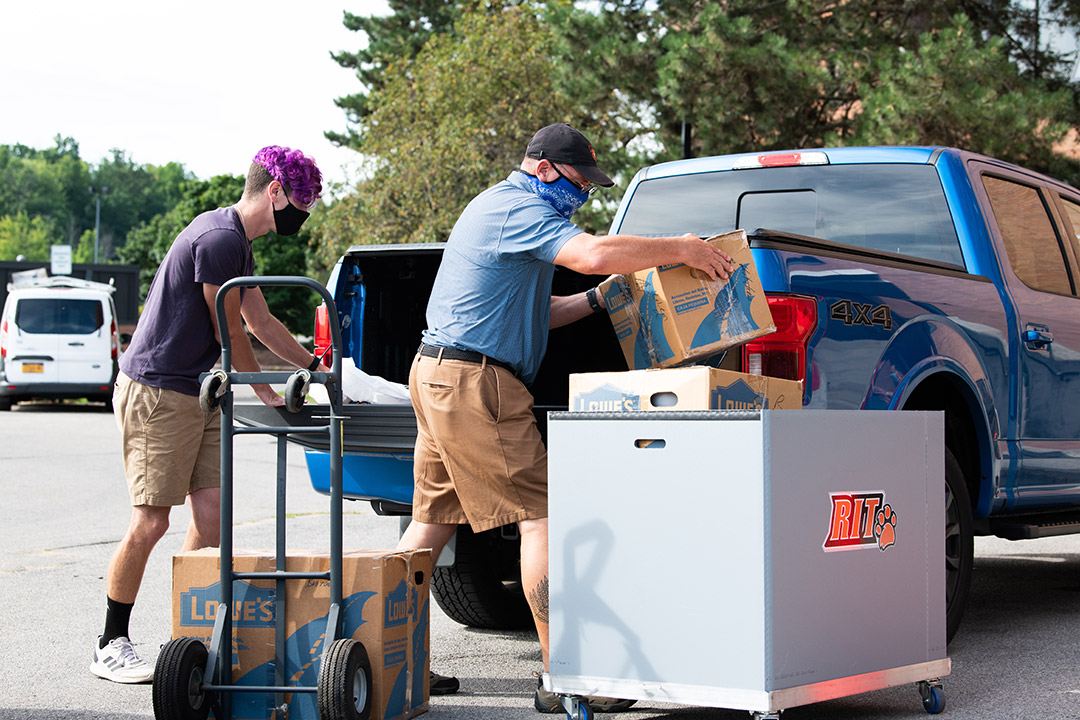 student and parent unloading pickup truck to move in to campus housing.