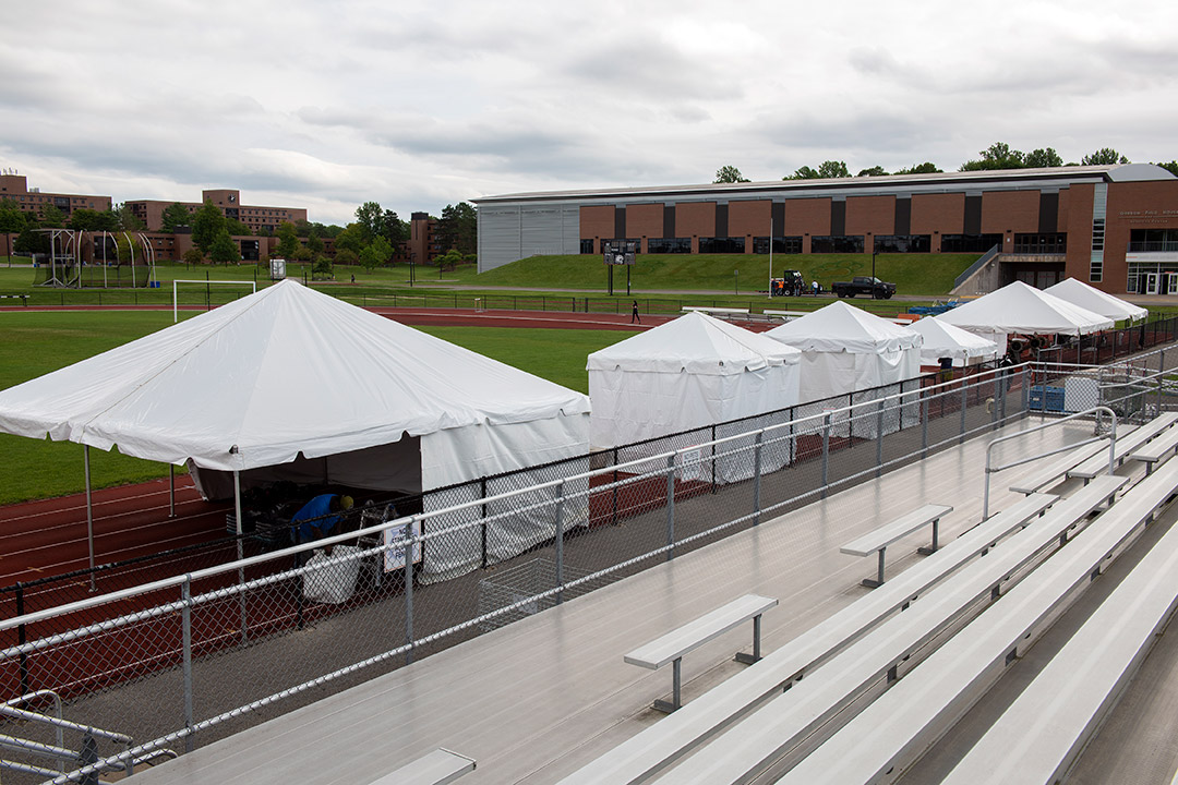 six tents on an outdoor track that house exercise equipment.
