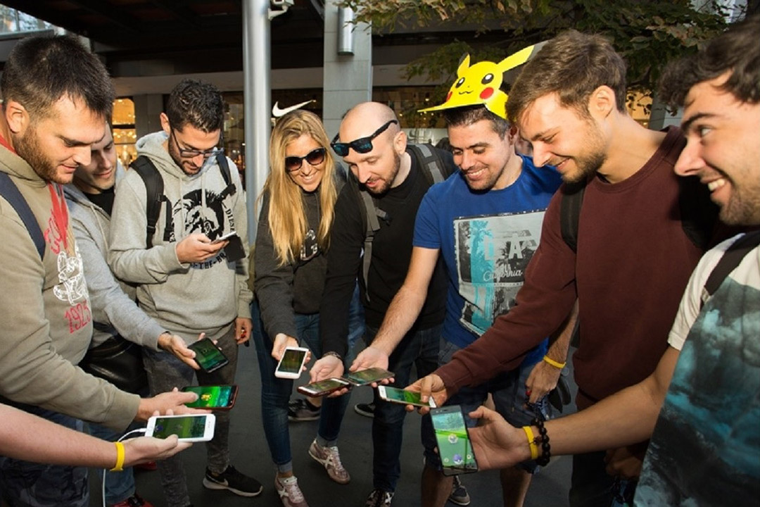 group of people in semicircle holding out their smartphones.