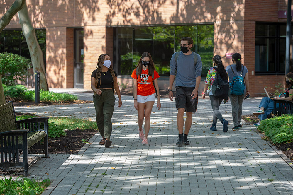 students walking outside wearing masks.