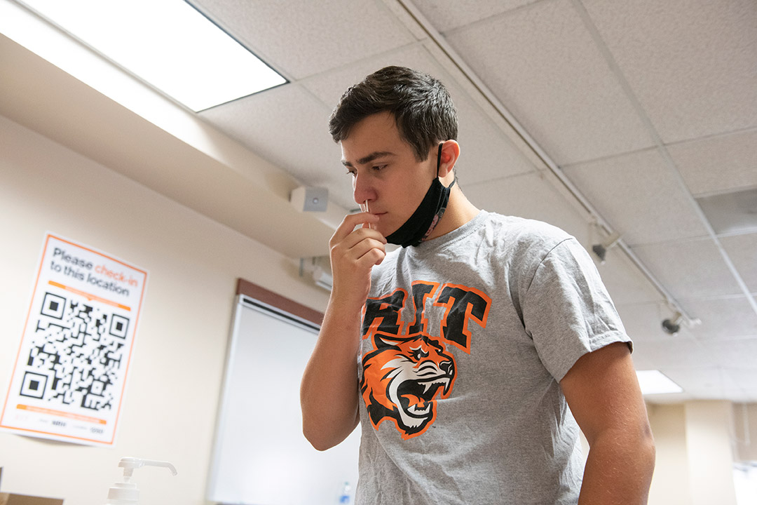 student swabbing nose for a COVID test.