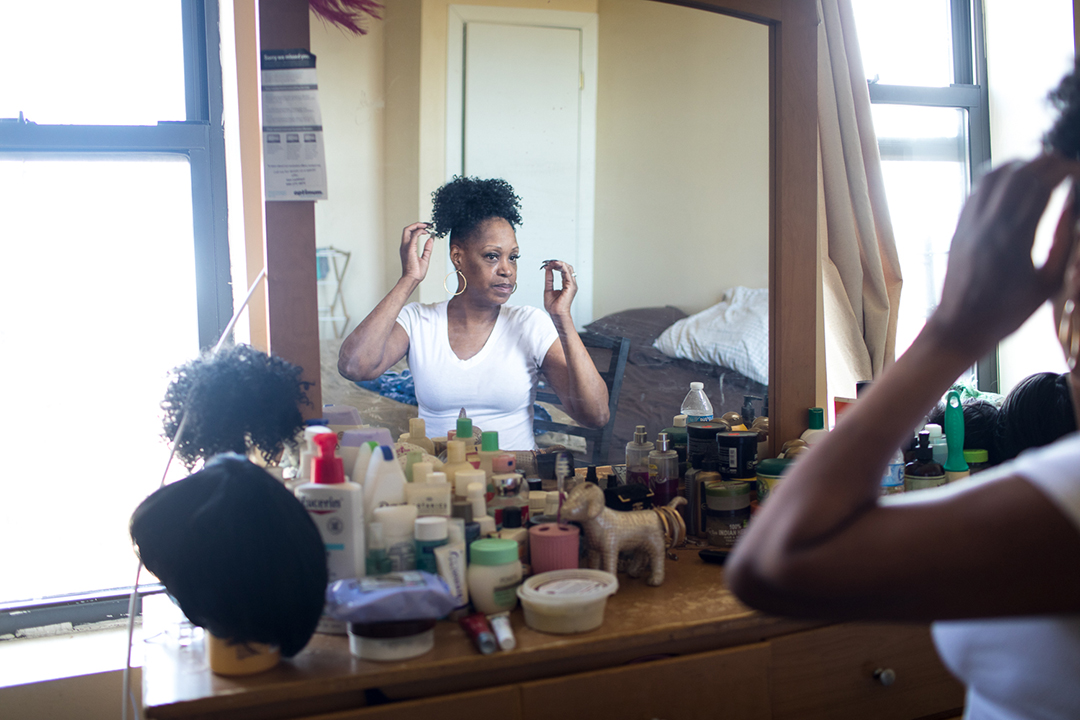 A woman looks into the mirror as she does her hair.