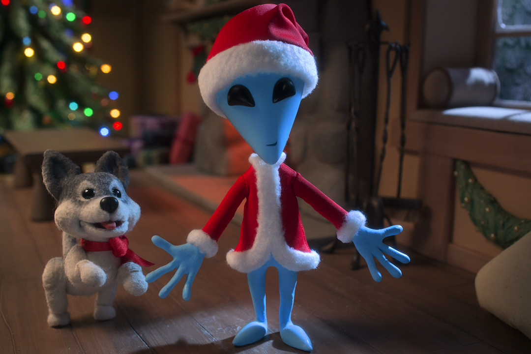 An animated alien dressed in a Santa suit.