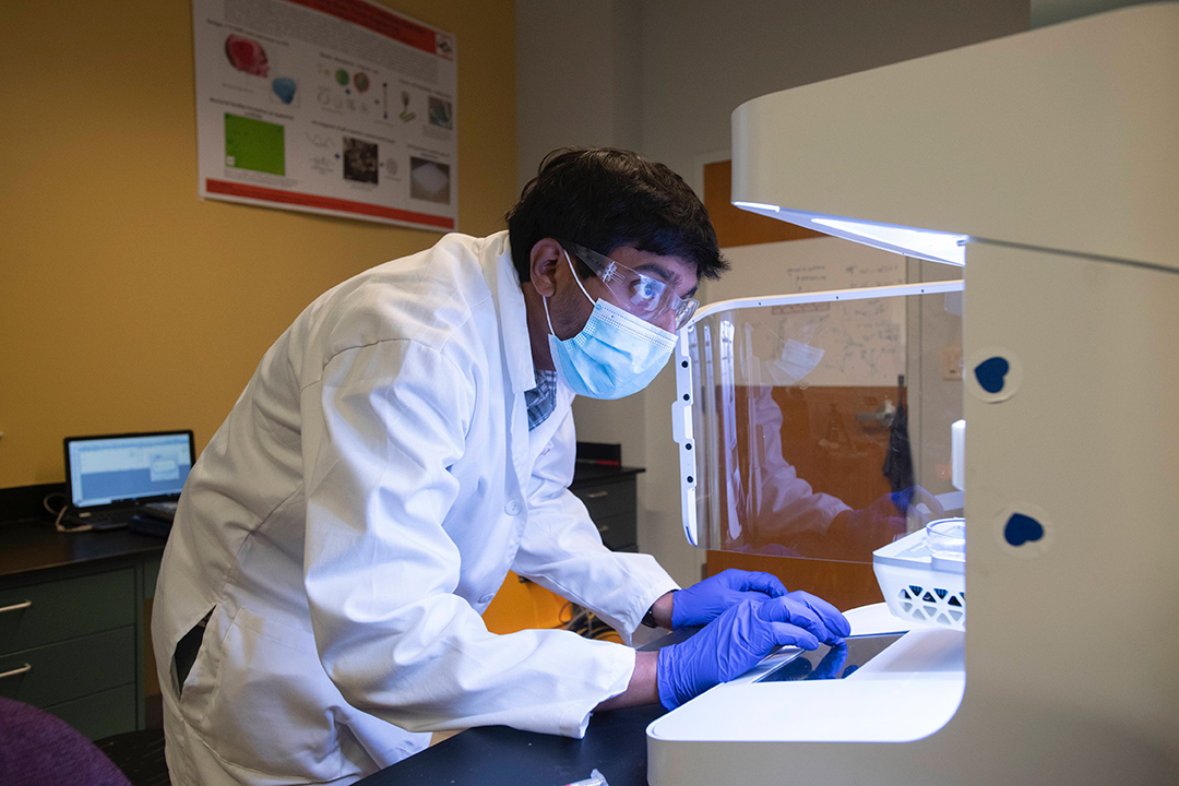 Ph.D. student in a lab coat working on a computer.