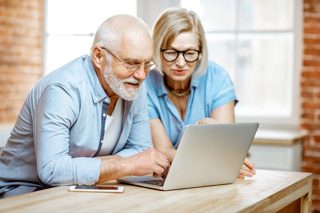 a man and a woman looking at a laptop together.