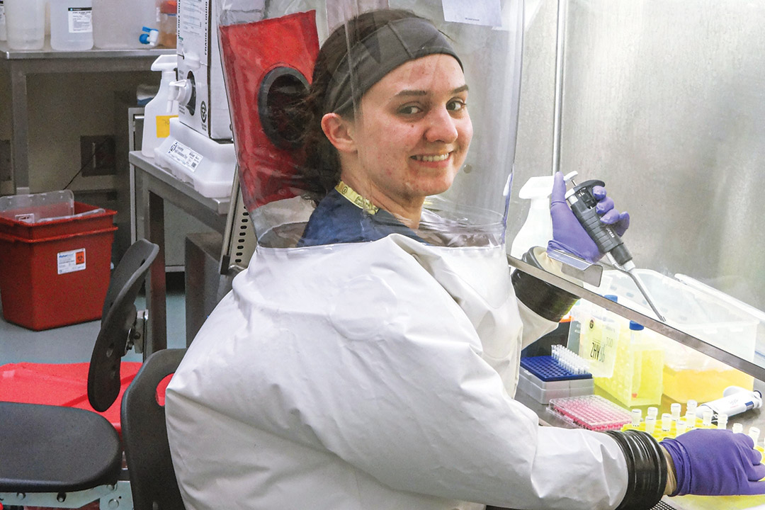researcher wearing a full protective suit using a pipette.