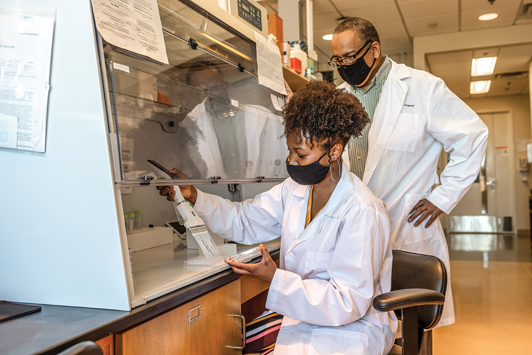 professor and student working with lab equipment.