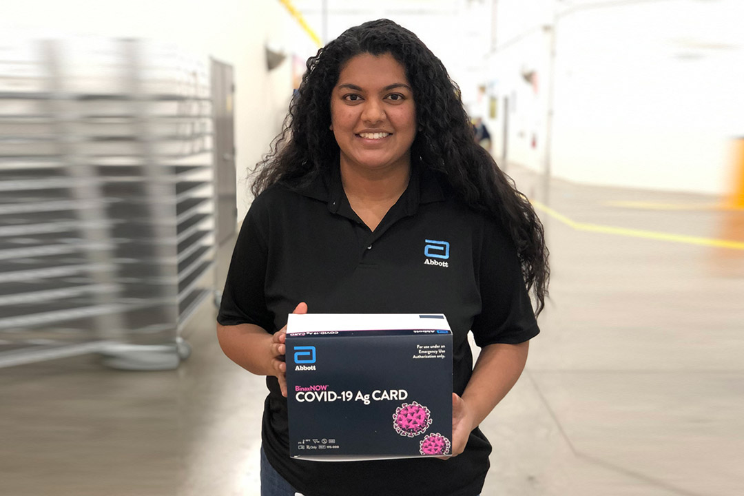 woman holding box of COVID-19 rapid tests.