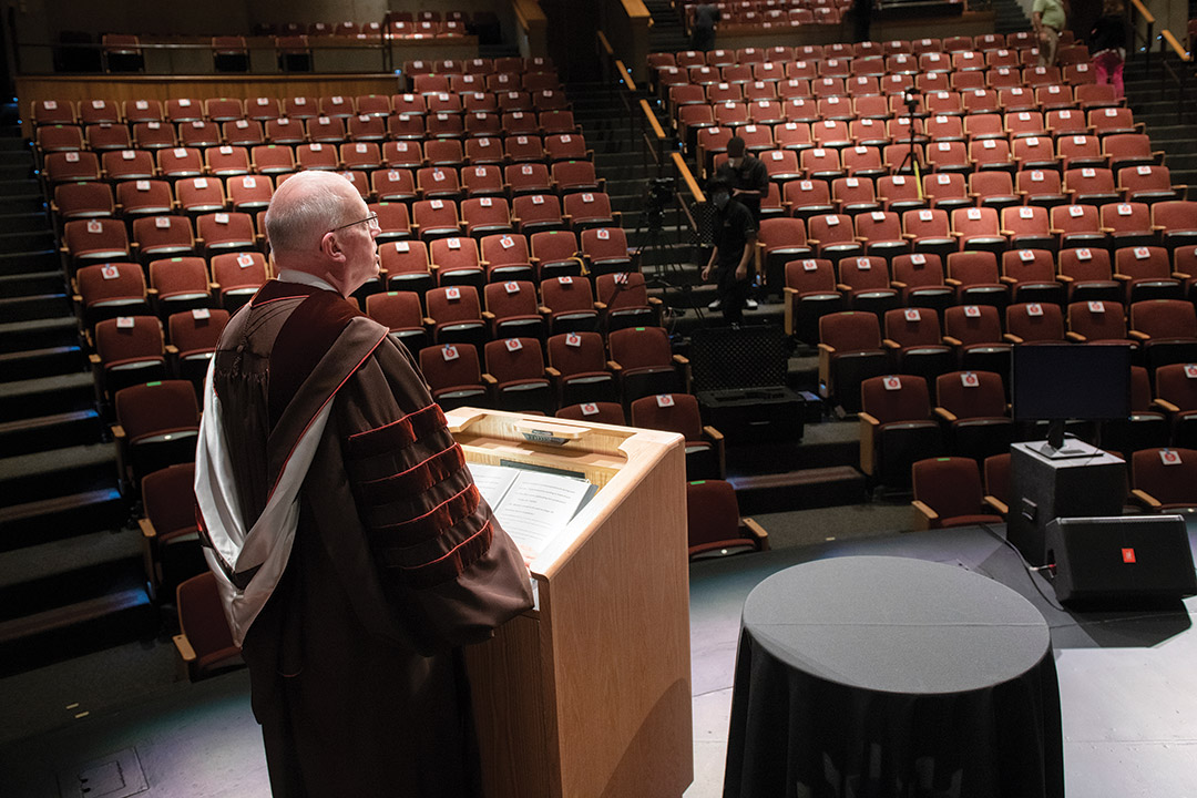 president David Munson speaking at podium to empty auditorium.