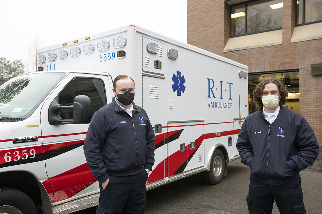 two masked members of RIT Ambulance in front of an ambulance