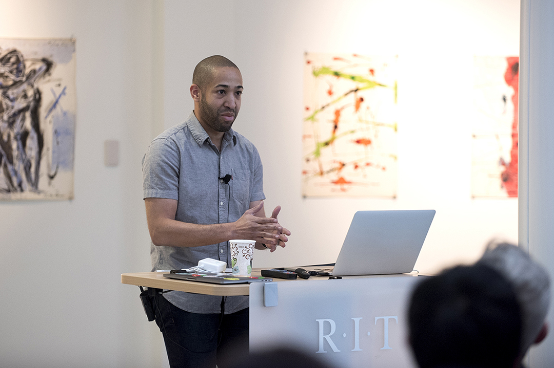 Jason Blythe speaks behind a lectern at RIT.