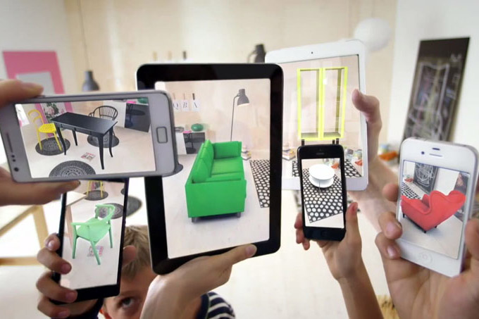 several smartphones and a tablet with an augmented reality app to display furniture in a room.