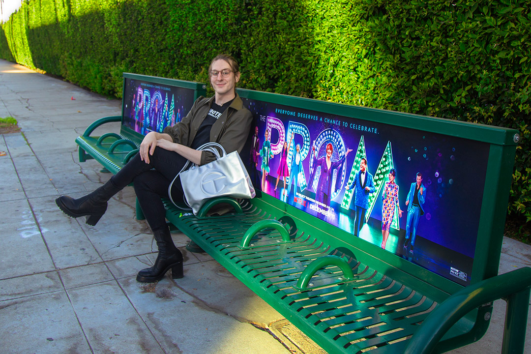 person sitting on a bench promoting the movie 'The Prom.'