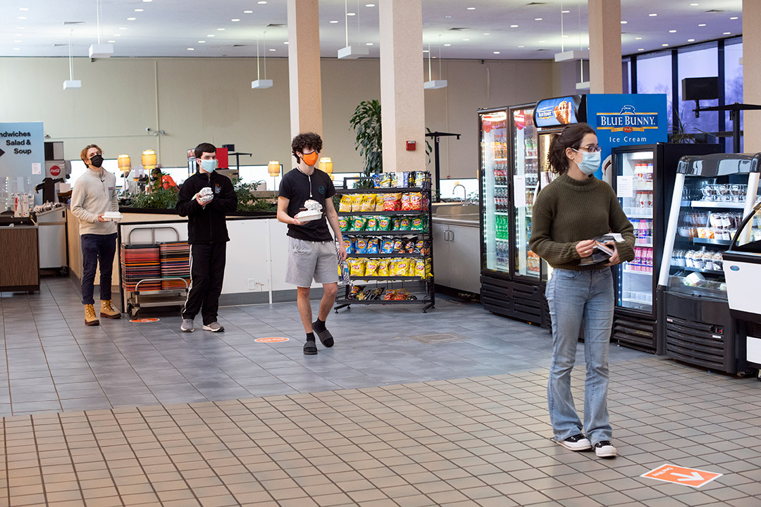 students waiting in line to pay for food in cafeteria.