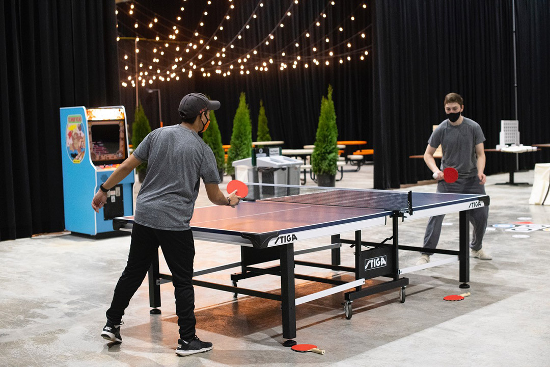 two students wearing face masks playing table tennis.