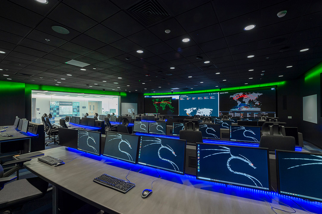 dark room with rows of tables with computer displays.