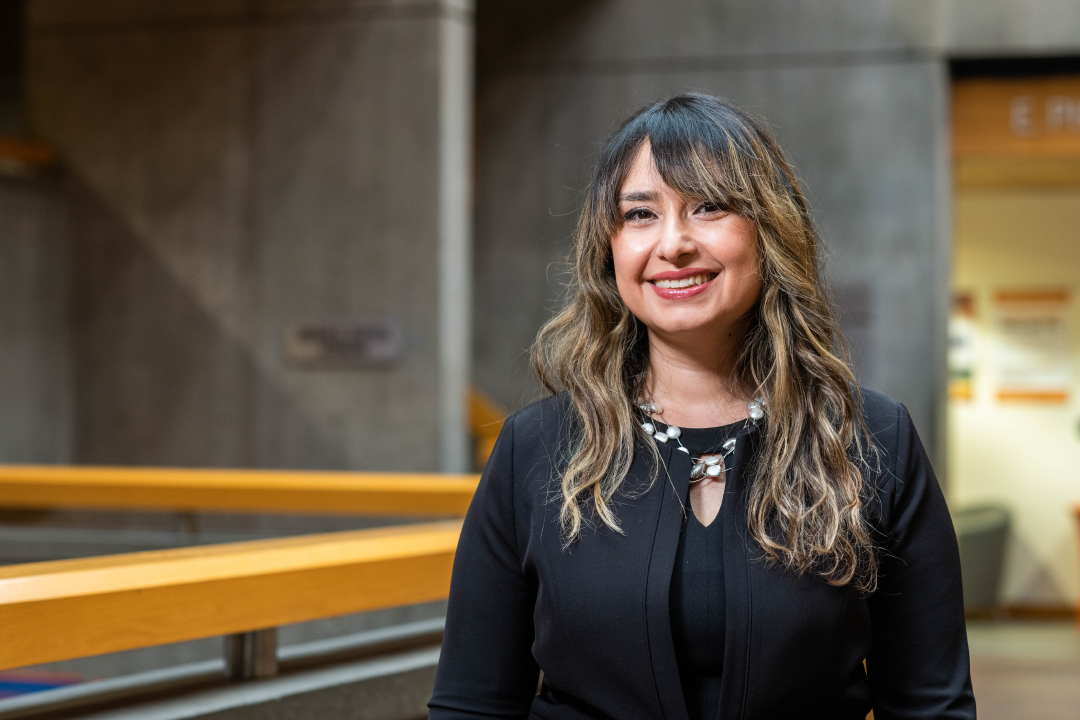 Duygu Akdevelioglu stands in the Saunders College of Business atrium and smiles at the camera