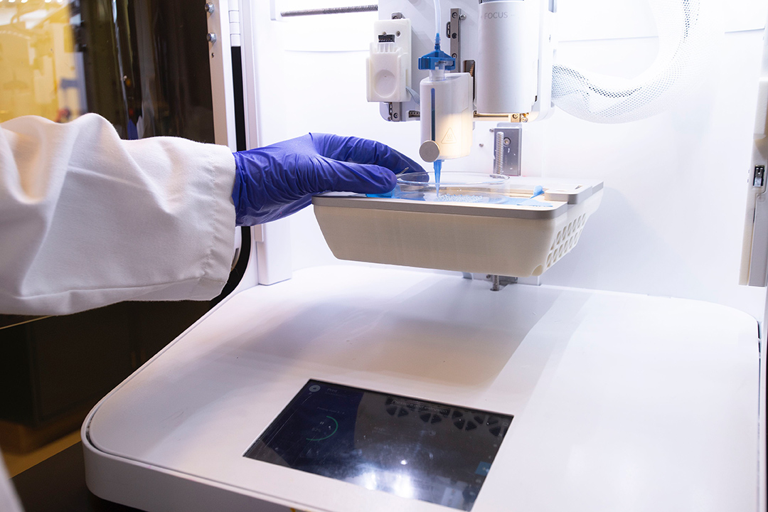 lab technician working with a pipette and imaging device.