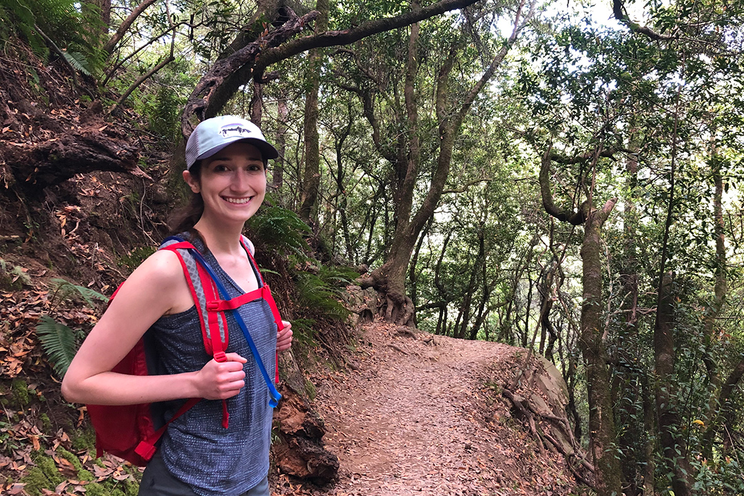 student hiking along wooded trail.