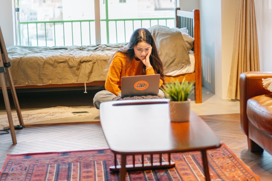 student working on laptop in a dorm room.