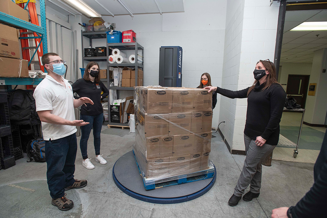 students and professor looking at new packaging equipment.