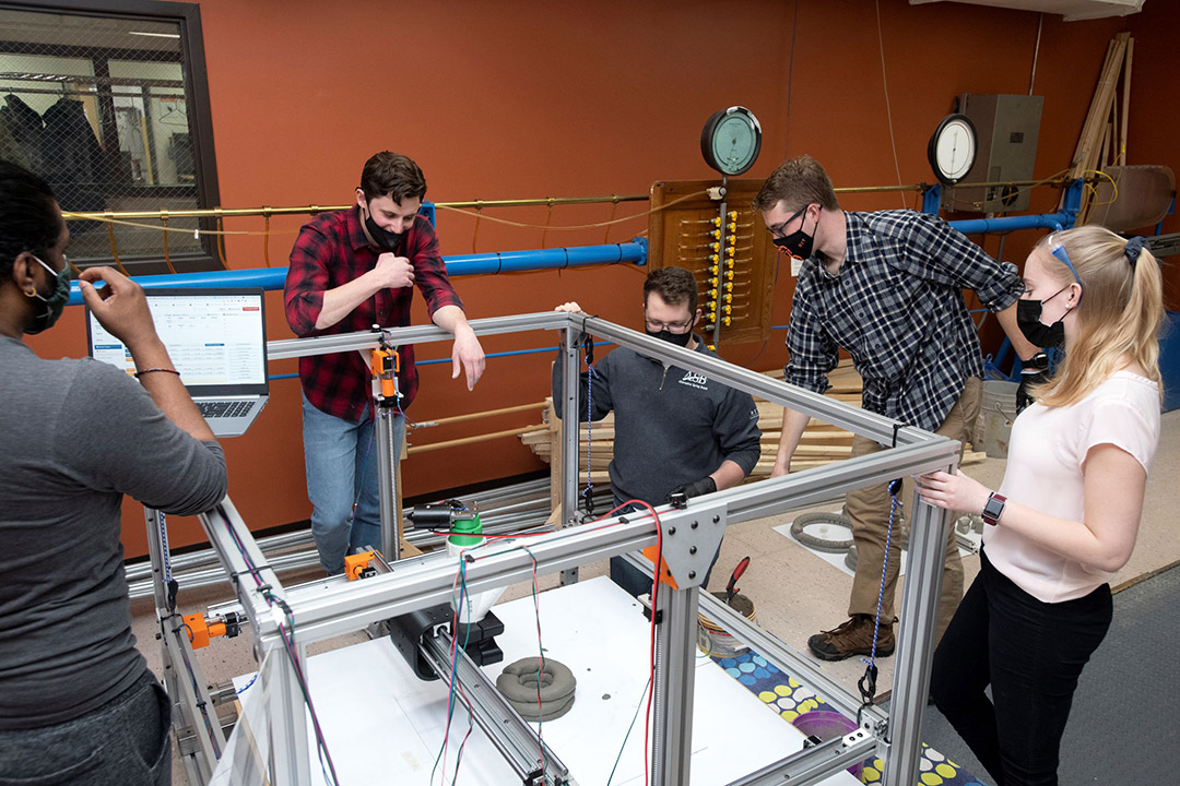 five students observing a 3D concrete printer.