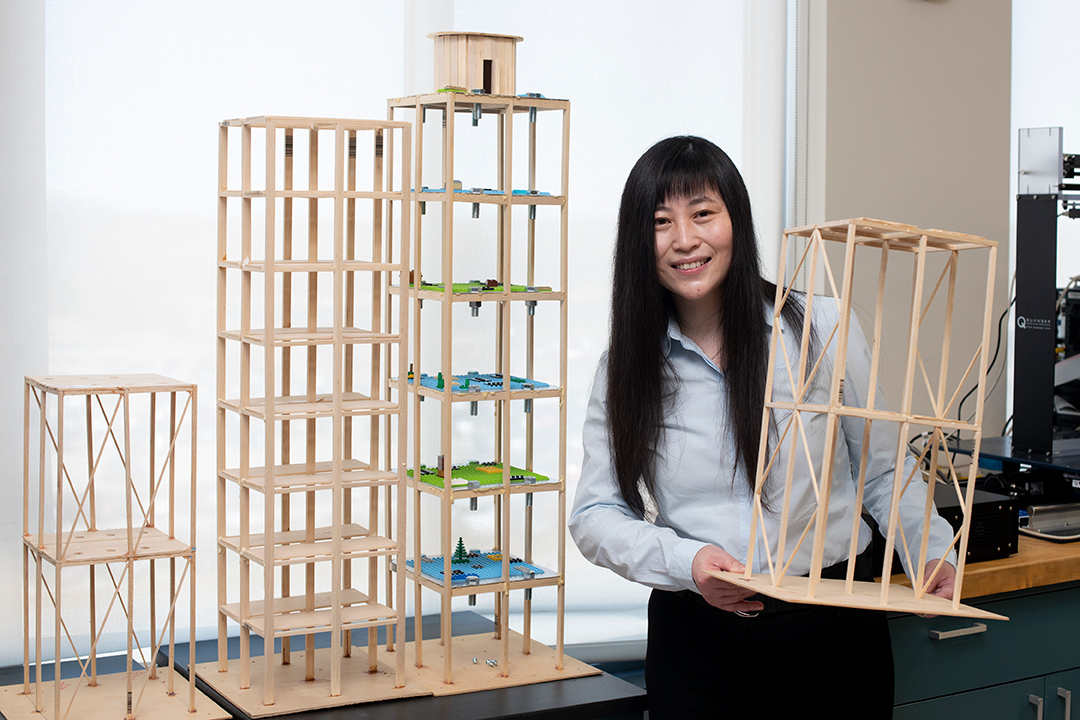 professor holding wooden models of skyscrapers.